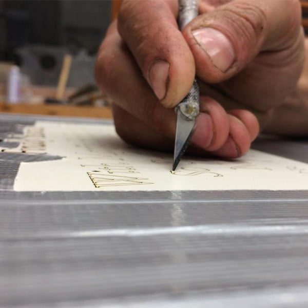 Monumental Sculptor William Todd hand-crafting a building sign in his workshop