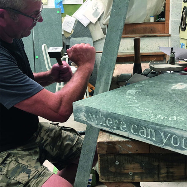 Monumental Sculptor William Todd hand-crafting a chisel inscription in a memorial in his workshop